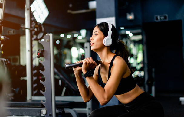 Подъем гантели рука упражнения Молодая женщина носить наушники во время тренировки Создать энергию для упражнений с музыкой упражнения, вес тела упражнения для здорового тела. - Фото, изображение