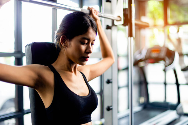 Ázsiai nő visel fitness ruhát Játssz a telefonon, viseljen fehér fejhallgatót, zenét hallgatni, pihenjen edzés közben, energiát generál a testmozgás inspiráció. - Fotó, kép