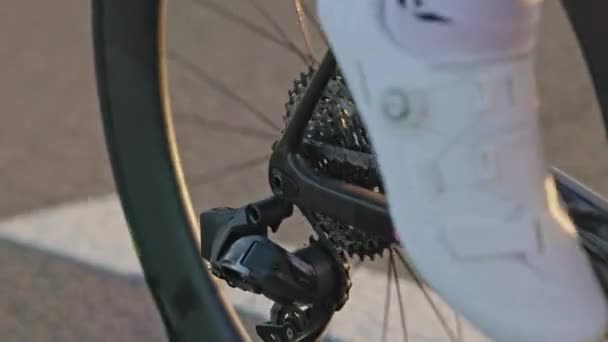 Close-up zicht op racefietsen aandrijfsysteem componenten getoond tijdens het fietsen in matig tempo. Trage beweging van de ketting door relevante derailleurs en over cassette en krukset. - Video