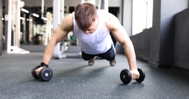 Hombre musculoso haciendo flexiones con mancuernas en el entrenamiento crossfit. Salud y deporte - Metraje, vídeo