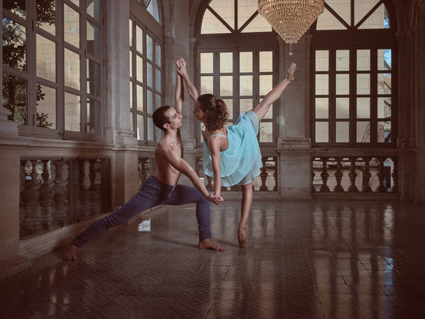 Seitenansicht der Ballerina in stehendem Split und hemdlosem Künstler, die sich beim Tanz im Ballsaal anschauen - Foto, Bild