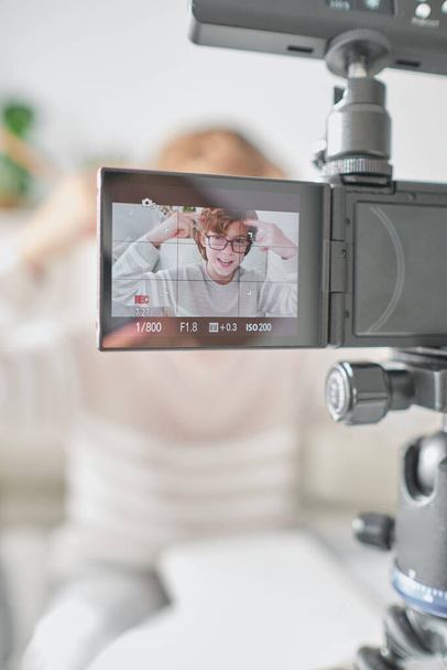 Menino em roupas casuais usando câmera profissional e filmagem de vídeo para blog enquanto passa o tempo em casa - Foto, Imagem