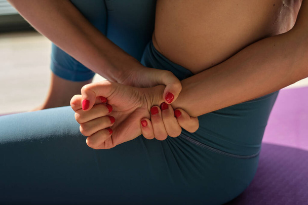Wysoki kąt upraw nierozpoznawalna kobieta w odzieży sportowej zaciskając ręce podczas treningu Marichyasana podczas sesji jogi - Zdjęcie, obraz