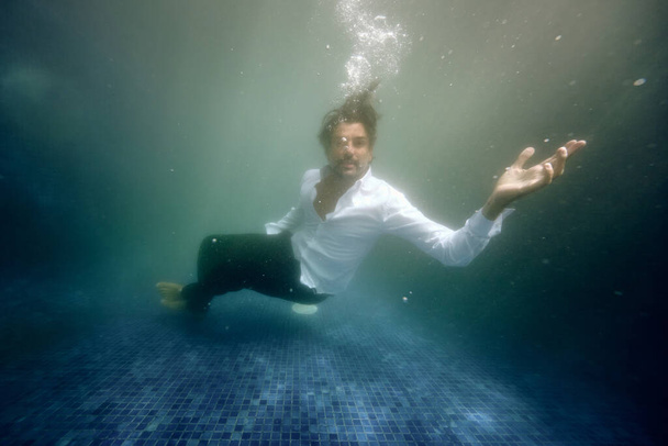 Podwodny widok sfrustrowanego samotnego mężczyzny tonącego w głębokiej wodzie basenu - Zdjęcie, obraz