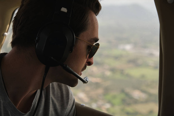 stock fotografie šťastného muže, který nosí letecké sluchátka a užívá si prohlídky lehkých letadel a dívá se oknem. - Fotografie, Obrázek