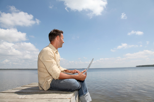 Homme avec ordinateur portable sur un ponton
 - Photo, image