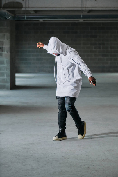 Comprimento total do misterioso modelo masculino com o rosto escondido sob o capô dançando no estacionamento subterrâneo - Foto, Imagem