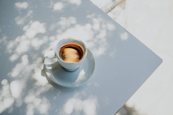 Tasse schwarzer Kaffee auf einem Tisch in einem Straßencafé im Sonnenlicht. Selektiver Fokus. Platz für Text. - Foto, Bild