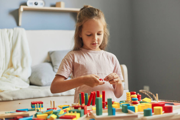 Childhood curiosity and discovery. Child's educational playtime. Creating a colorful learning environment. Adorable little girl playing with wooden educational toys at home - Photo, Image