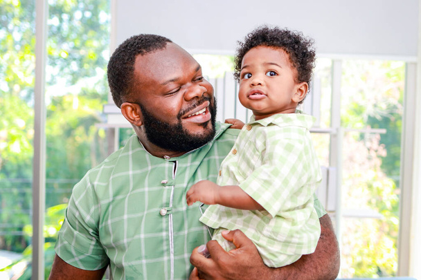 Portret van een gelukkige Afro-Amerikaanse vader en zoon in huis. Gezinsconcept. - Foto, afbeelding