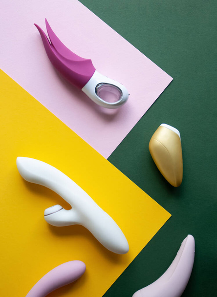 Колекція різних типів секс-іграшок на рожевому, зеленому та жовтому тлі. - Фото, зображення