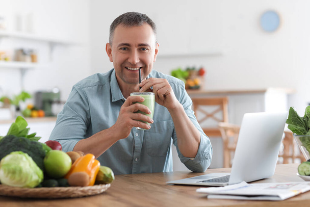 Felnőtt férfi ivás friss növényi smoothie a konyhában - Fotó, kép