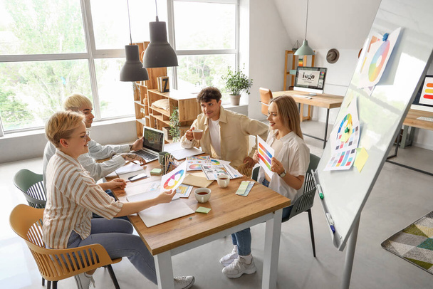Tým grafiků pracujících s barevnými paletami u stolu v kanceláři - Fotografie, Obrázek