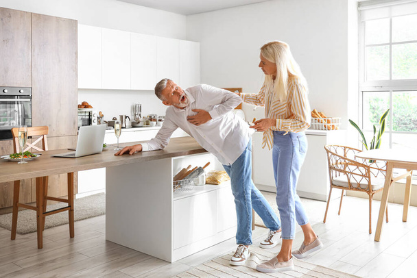 Kypsä nainen ja hänen miehensä ottaa sydänkohtaus keittiössä - Valokuva, kuva