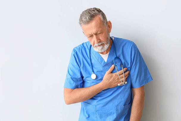 Зрілий лікар має серцевий напад на світлому фоні - Фото, зображення
