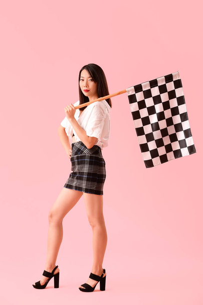 Beautiful Asian woman with racing flag on pink background - Photo, Image