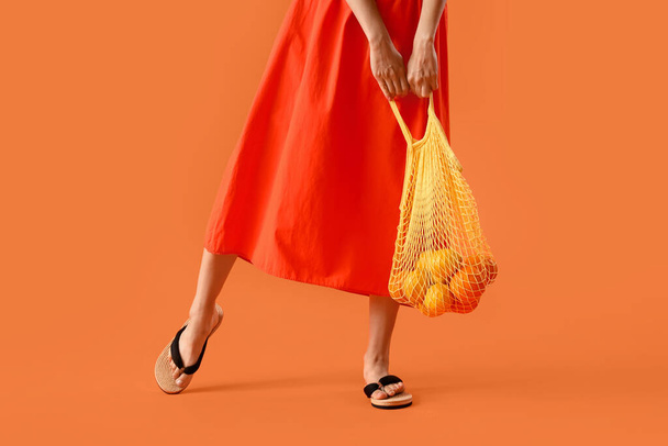 Beautiful woman in summer clothes and with eco bag on orange background - Photo, Image