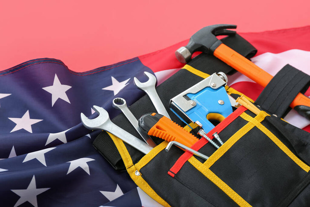 Cintura con diversi strumenti e bandiera USA su sfondo rosso. Festa del lavoro - Foto, immagini