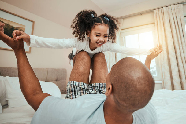 Dad, child and playing on bed flying for fun, quality time or bonding together in home, bedroom or girl in airplane game. Happy, father and daughter in air with knees and arms raised with freedom. - Photo, Image