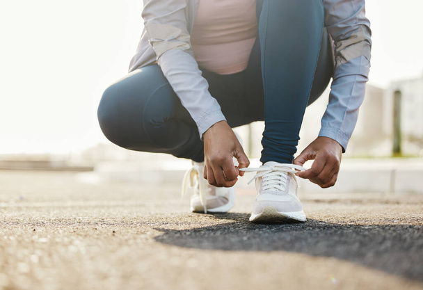 Fitness, runner and woman tie shoes outdoor in the road for running workout in the city. Sports, health and closeup of female athlete tying her laces for cardio exercise for race or marathon training. - Photo, Image