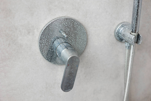 Grifo de mezclador de ducha calcificado sucio, grifo con cal en él, placa de agua dura, ducha cromada, foto de cerca. Cuarto de baño con azulejos gris interior - Foto, Imagen