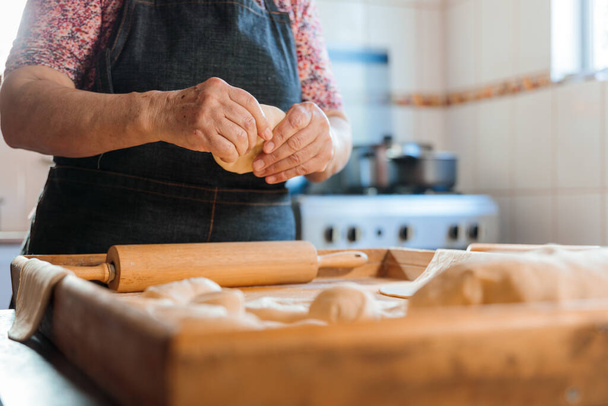 Відверте захоплення невідомої латиноамериканки, що виготовляє тісто з руками та рулонним штифтом на сільській домашній кухні. Високоякісна фотографія - Фото, зображення
