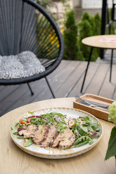 Assiette avec salade de viande de veau sur une table en bois sur la terrasse. - Photo, image