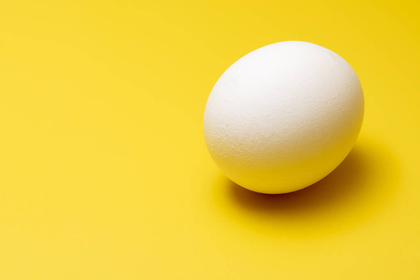 Um ovo ao ar livre sobre um fundo amarelo - Foto, Imagem