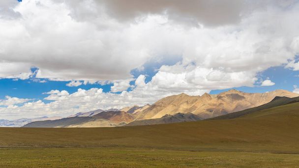 Een open landschap aan de hogere uithoeken van Ladakh met bruine weiden en wolken - Foto, afbeelding