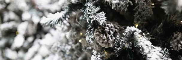 Straat decoratie voor Kerstmis als achtergrond. Kerstboom bedekt met vorst met kegels en bloemenslinger van dichtbij. Vrolijk Kerstfeest en Gelukkig Nieuwjaar thema. - Foto, afbeelding