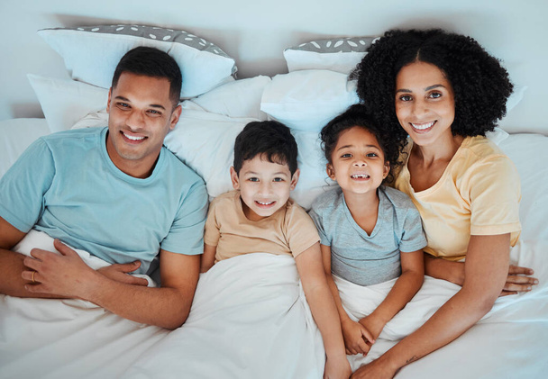 Top view, bed and portrait of parents with children for bonding, quality time and affection in morning. Happy, family and above of mother, father and kids in bedroom for fun, sleeping and relaxing. - Photo, Image