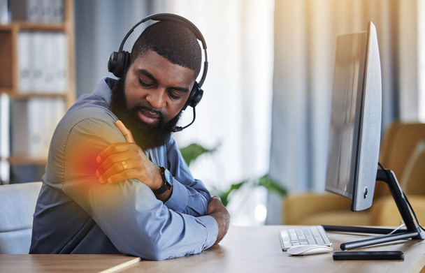 Call center, customer support and black man with shoulder pain, muscle strain and injury at desk. Telemarketing, business and male consultant with inflammation for communication, crm help and contact. - Photo, Image