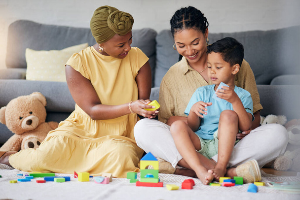 Toys, child and a gay family playing on a home floor for development, education and learning. Adoption, lesbian or LGBT women or parents and kid together in a lounge for quality time with fun blocks. - Φωτογραφία, εικόνα