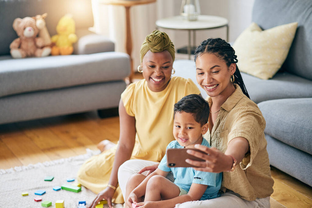 Lesbian, women and son in home for selfie, smile or care with toys, post or blog on floor in living room. Mother, male kid and happy for gay love, bonding and memory on social network in family house. - Foto, imagen