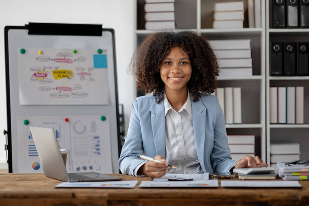 Američanka pracující v startupní společnosti, americká podnikatelka pracující v kanceláři, prohlíží si finanční dokumenty a prodejní data, která shrne před schůzkou s vedoucími pracovníky. - Fotografie, Obrázek