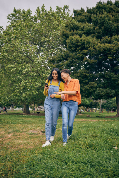 Women, park and girl friends with phone outdoor with laughing at meme and social media. Urban, city garden and mobile with gen z, young and female people on holiday with freedom and happy in spring. - Photo, Image
