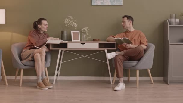 Modern blank gay paar zitten aan tafel in hun appartement met gesprek - Video