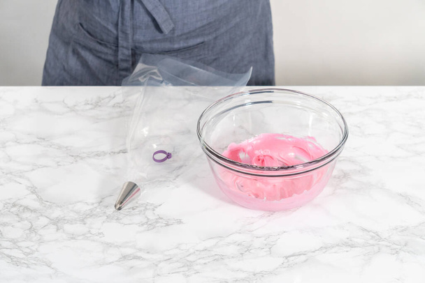 Mescolare il colorante alimentare rosa nella meringa per cuocere i biscotti di meringa pasquali. - Foto, immagini