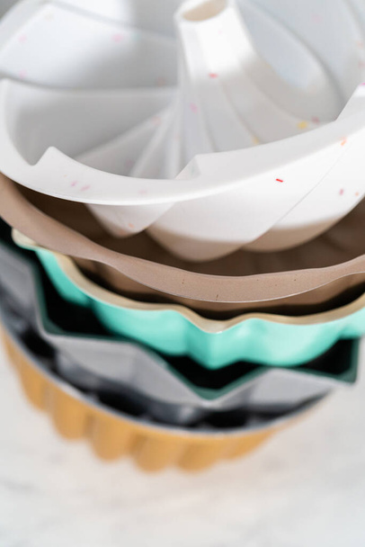 Stapel van verschillende kleuren en vormen bundt cake pannen. - Foto, afbeelding