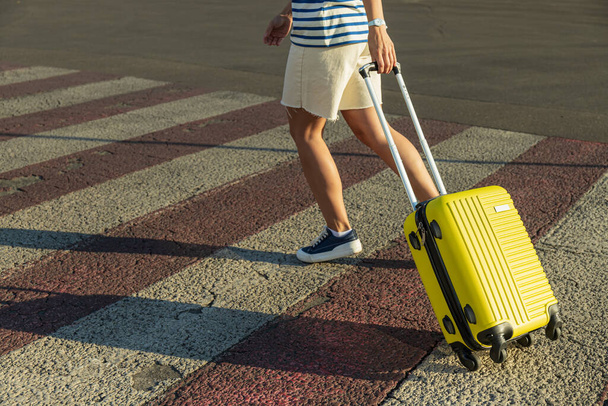 Woman with yellow suitcase on road in the city - Photo, Image