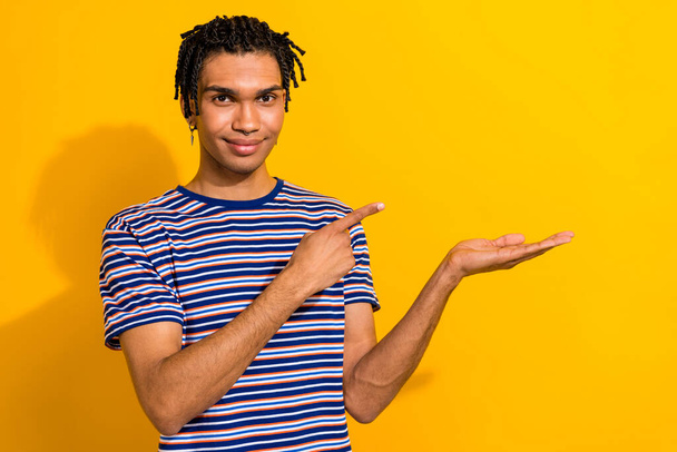 Фото позитивного мужчины носить модный наряд руку представляя пустое пространство общей продажи изолированы на желтом фоне цвета. - Фото, изображение