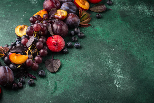 Assortimento di prugna viola, uva, mirtillo e basilico su fondo viola - Foto, immagini