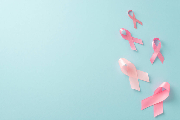 Configuración de detección temprana del cáncer de mama. Vista superior plana puesta de símbolos de cinta rosa sobre fondo azul pastel. Ideal para campañas médicas - Foto, Imagen