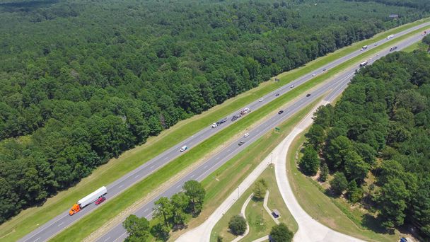 Плотное движение по автомагистрали I-10 и выход из зоны отдыха Гринвуд в Луизиане, окружающие пышные зеленые сосны Loblolly Pinus taeda продукты лесной промышленности. Остановка для отдыха на воздушном шоссе - Фото, изображение