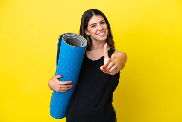 sport Italiaanse vrouw gaat naar yoga klassen geïsoleerd op gele achtergrond tonen en heffen van een vinger - Foto, afbeelding