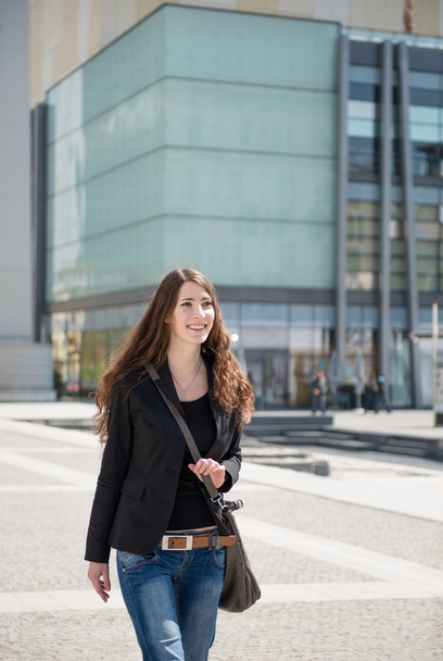 Young woman with laptop bag walking street - Valokuva, kuva