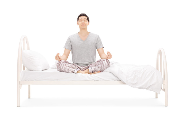 Calm guy meditating on bed - Foto, Imagem