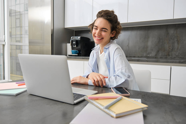 Πορτρέτο του χαμογελαστού νεαρή γυναίκα συνδέεται με online webinar, σπουδές στο σπίτι στο τηλεχειριστήριο, κοιτάζοντας το φορητό υπολογιστή με χαρούμενο πρόσωπο, τους ανθρώπους των εκπαιδευτικών μέσω της ιστοσελίδας δάσκαλος. - Φωτογραφία, εικόνα