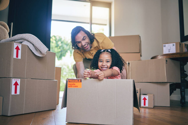 Father, portrait and kid in box of new home for games, fun and freedom in real estate apartment. Excited dad, girl child and interracial family play in cardboard boxes for race while moving to house. - Photo, Image