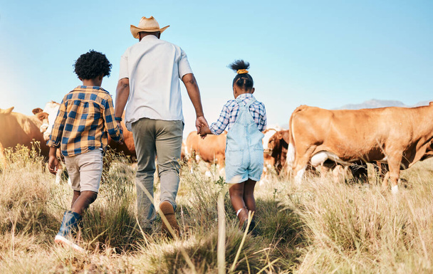 Farm, cows and father holding hands with children in countryside for ecology, adventure and vacation. Family, sustainable farming and back of dad with kids for bonding, relax and learning with animal. - Photo, Image